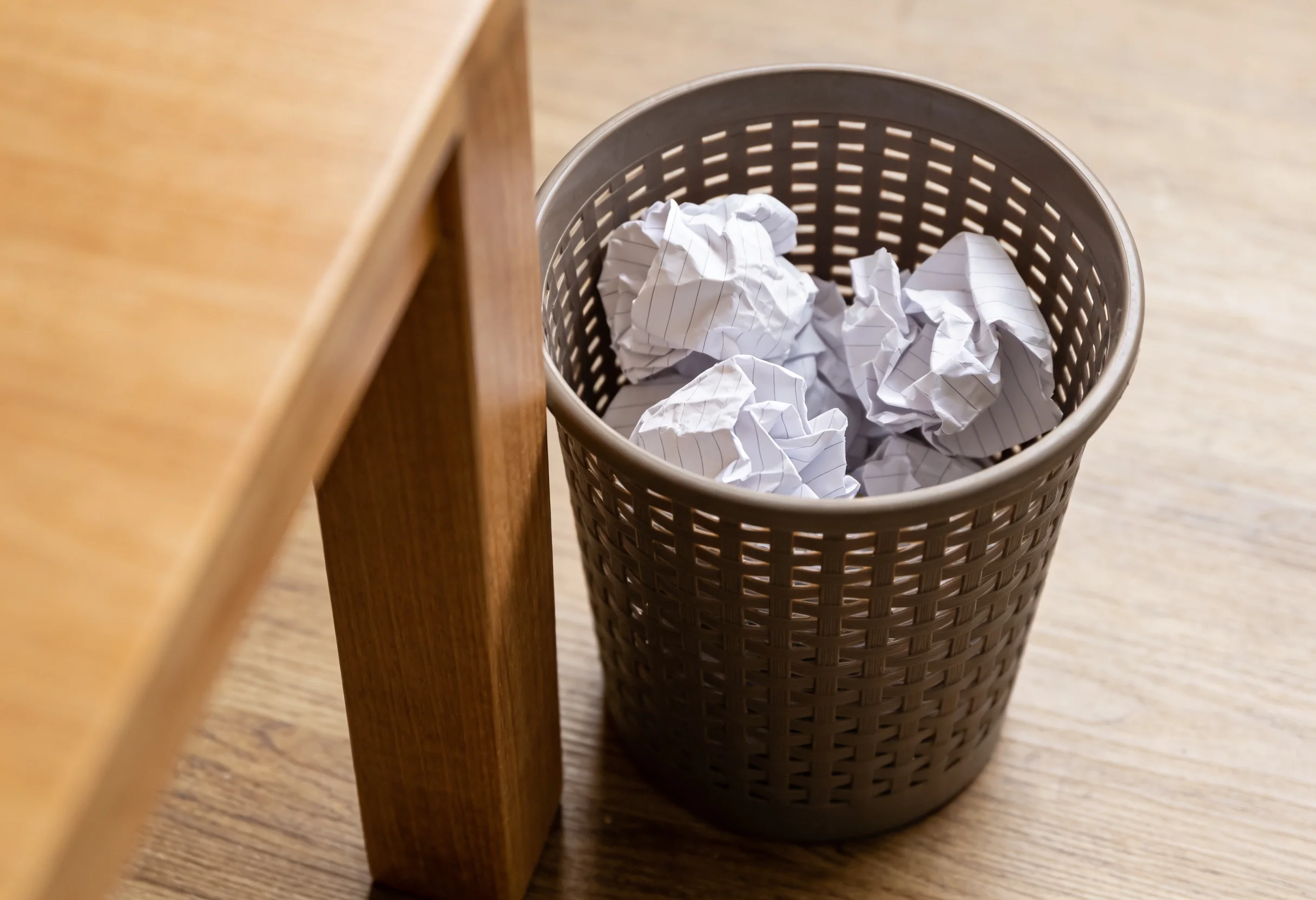 Crumpled bet slips in a wastepaper basket next to a desk