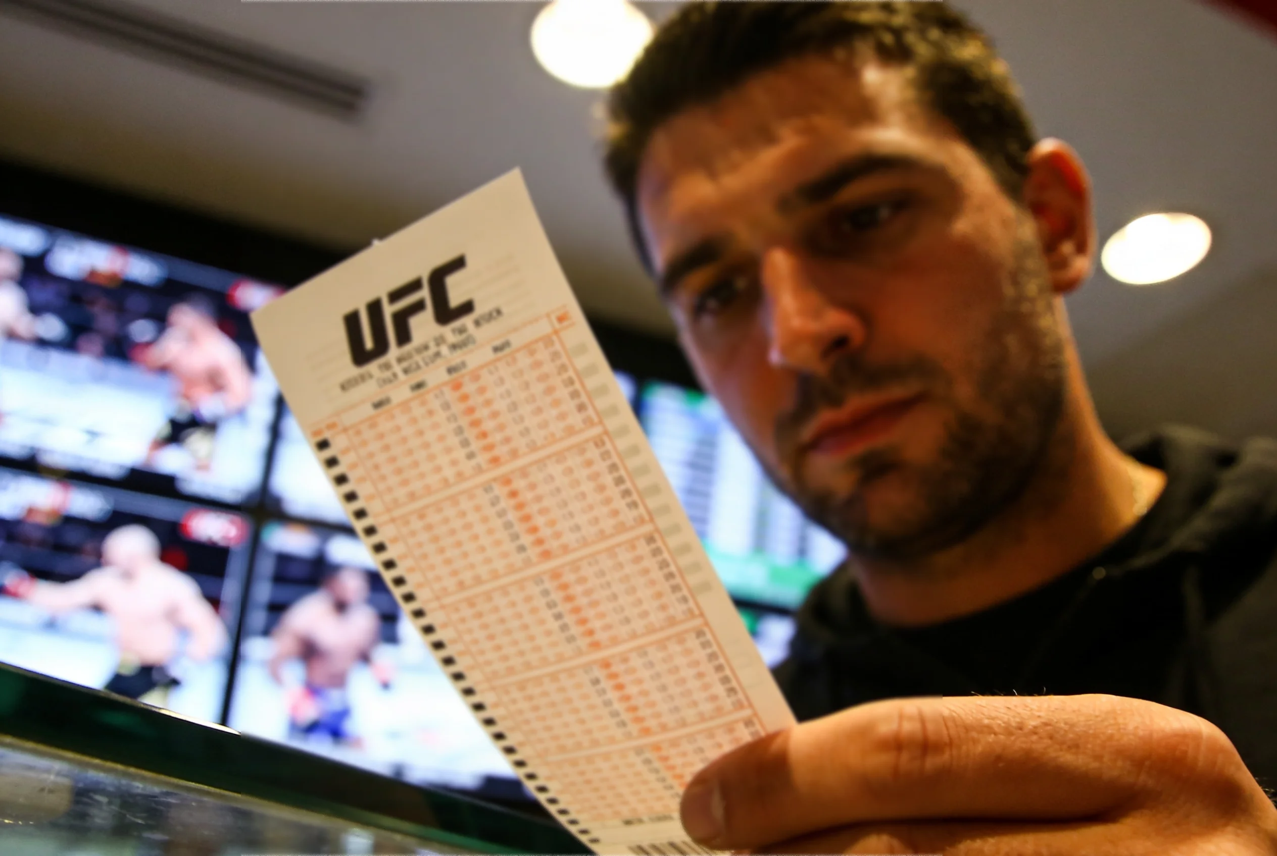 Close-up of a punter studying UFC fight odds on a betting slip inside a sportsbook