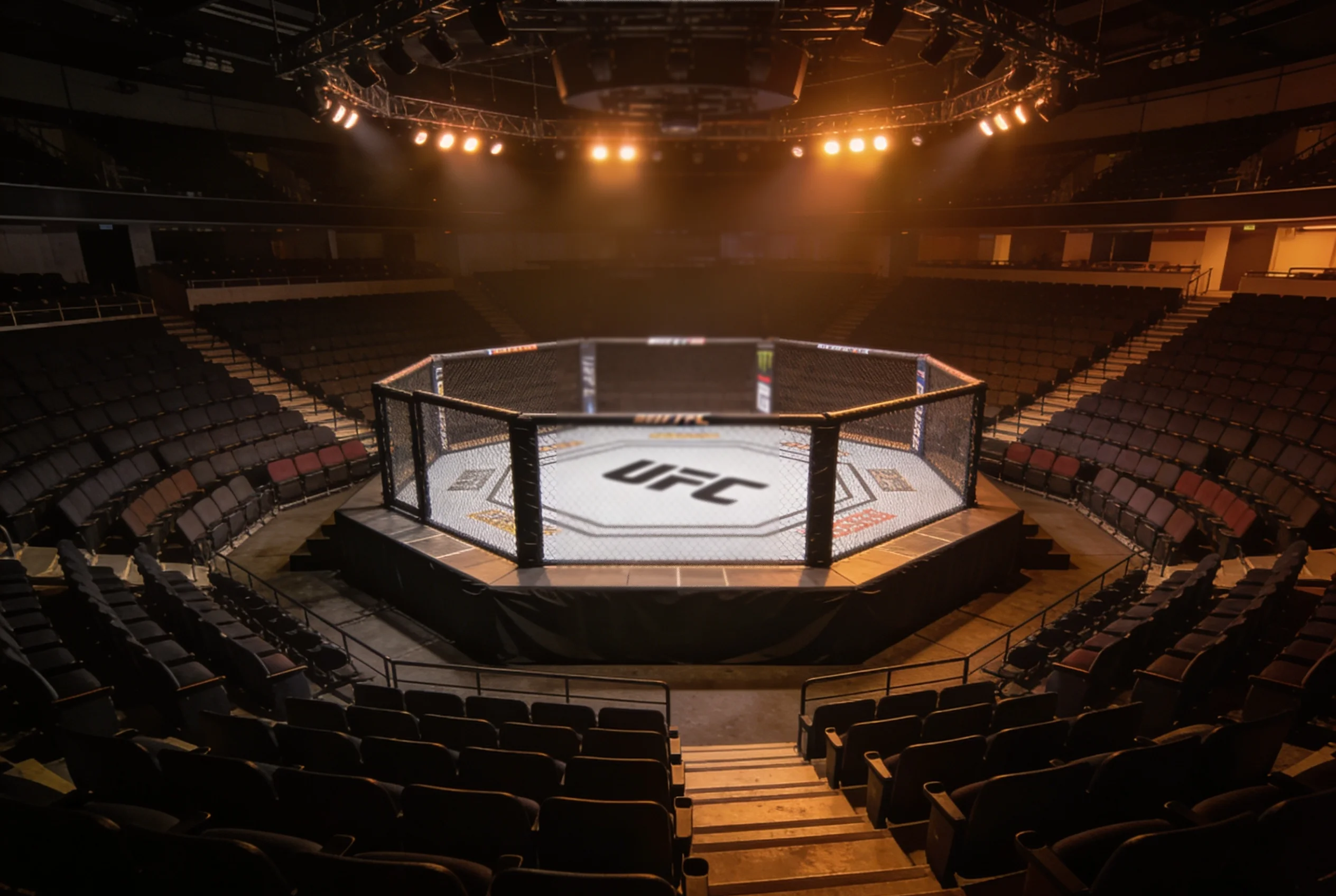 Small UFC event venue with an empty octagon under subdued lighting before a Fight Night card