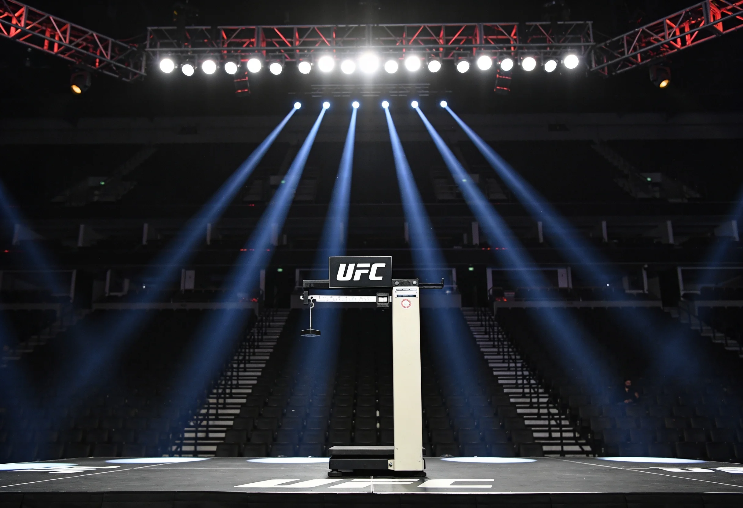UFC weigh-in stage with a digital scale and bright spotlights in an empty arena